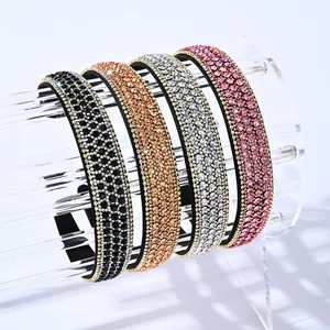 Détail de quatre serre-têtes larges en strass aux tons noir, doré, argenté et rose