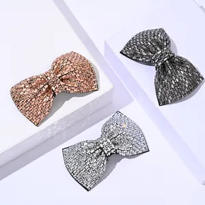 Three crystal bow hair clips in rose gold, gunmetal and silver on white display stands