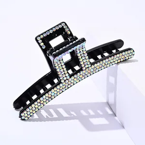 Detail of square black hair claw clip with sparkling colorful rhinestones on white block
