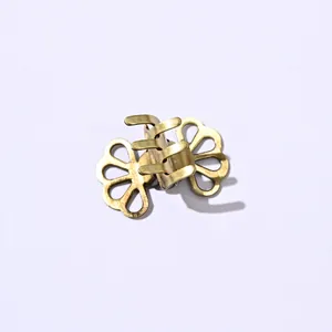 Detailed close-up of a small vintage golden metal hair claw with hollow floral patterns