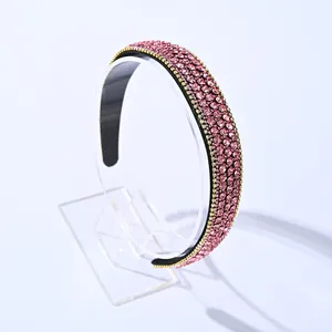 Serre-tête luxueux en strass roses avec bordure dorée sur un support de présentation clair