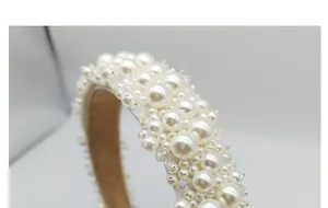 Primer plano de diadema de novia hecha a mano con perlas brillantes y forro de tela blanca elegante