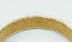 Detalle macro de diadema de novia hecha a mano con perlas y cristales en terciopelo blanco