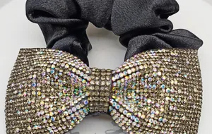 Dettaglio di un elastico per capelli in raso nero con fiocco di cristalli e strass AB
