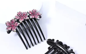 Detail van zeven-tands haarkam met drie roze strass bloemen op zwarte hars basis
