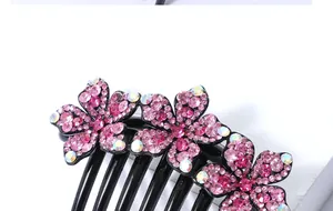 Macro detail van drie roze strass bloemen op een zwarte 7-tands haarkam accessoire
