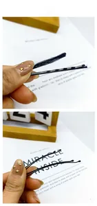 Close-up of black wave-shaped metal hairpins with a glossy finish for hairstyling