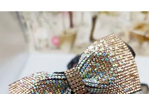 Dettaglio di un elastico per capelli a fiocco con strass colorati e champagne lucidi