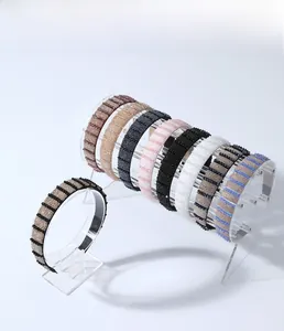 Detail view of 8 different beaded fabric headbands in assorted colors on acrylic display