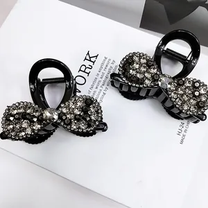 Pinces à cheveux en acrylique noir avec strass disposées sur un livre blanc