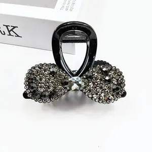 Vue détaillée de la pince à cheveux nœud noir ornée de strass gris foncé et noirs étincelants