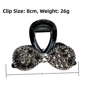 Détail de la pince à cheveux 8cm noire ornée de strass gris foncé et d'un ressort en métal