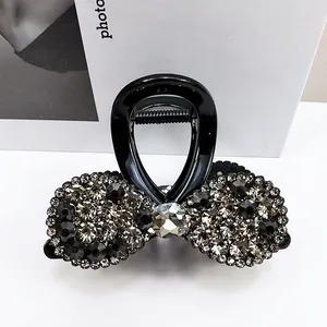 Détail d'une pince à cheveux noire avec nœud orné de strass gris étincelants et gemme