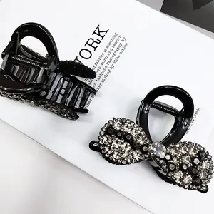 Gros plan de pinces à cheveux noires avec un nœud en strass étincelant et mécanisme