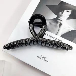Detail of elegant black hair claw clip with rhinestones on a white display card