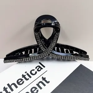 Macro detail of large black shark hair claw clip with rows of sparkling rhinestones