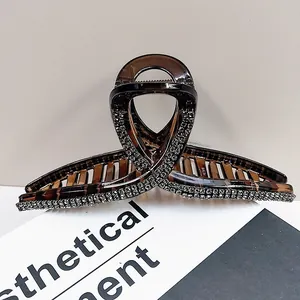 Close-up of large amber rhinestone hair claw clip with silver crystals on elegant grey background