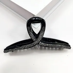 Macro shot of large black ribbon hair claw clip featuring elegant rhinestone border detail