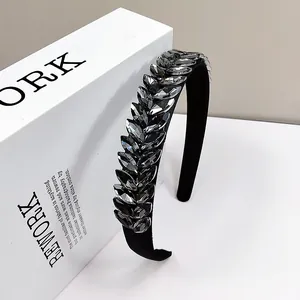 Diadema elegante de terciopelo negro con cristales grises brillantes sobre libro blanco