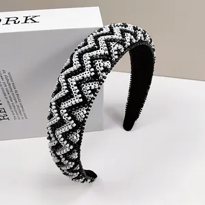 Close-up van brede gevoerde hoofdband met handgemaakte zwart-witte kralen in geometrische patronen