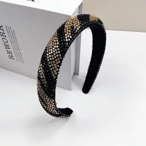 Dettaglio del cerchietto fatto a mano con perline nere e dorate a strisce diagonali