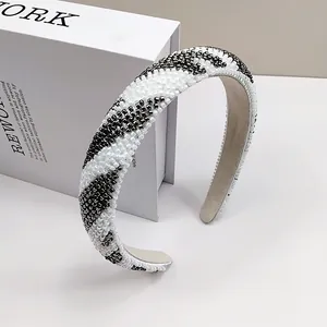 Dettaglio di un cerchietto con perline e motivi a onde argento e bianco su fascia larga