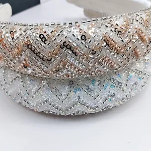 Macro detail van handgenaaide kralen en pailletten op een witte brede satijnen hoofdband