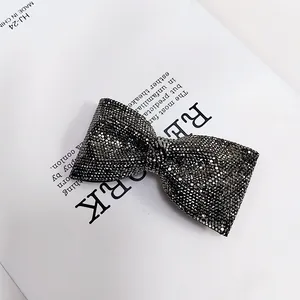 Macro di fermaglio per capelli a fiocco nero con strass luccicanti su rivista bianca