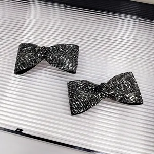Dettaglio di due fermagli per capelli a fiocco nero con glitter fini e finitura brillante