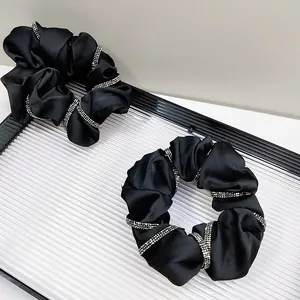 Close-up of black satin scrunchies featuring luxury silver rhinestone wrap decorations