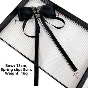 Detail of black satin bow hair clip with crystal butterfly and 22cm long ribbon