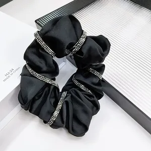 Detailed view of elegant black satin scrunchie decorated with sparkling rhinestones