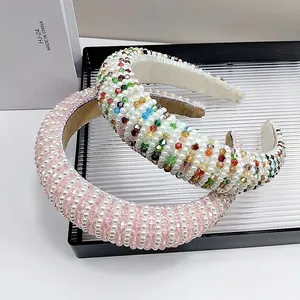 Baroque style wide headband with pink crystals and white pearls on a black tray