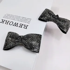 Dettaglio di lussuosi fermagli a fiocco nero con strass scintillanti su sfondo bianco