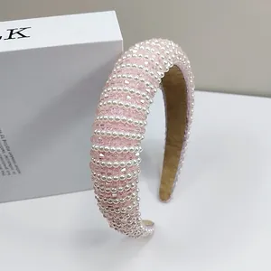 Detailed close-up of pink crystals and white pearls on a wide padded headband