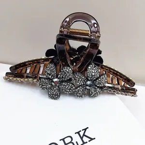 Détail macro d'une pince à cheveux en écaille avec strass floraux et texture velours