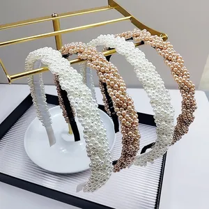 Detail shot of wide braided pearl headband on a display stand showing elegant texture