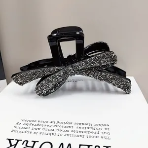 Détail de la pince à cheveux noire élégante ornée d'un nœud en strass gris et marque HJ-24