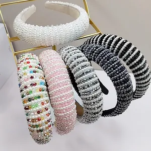 Detail of five handmade pearl and crystal headbands in assorted colors on a gold rack