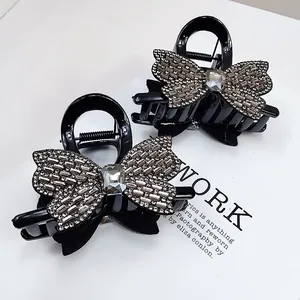 Détail des pinces à cheveux papillon noires avec strass scintillants sur papier blanc