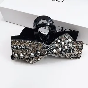 Detailed macro view of black bow hair claw clip with gradient rhinestones and sparkling finish