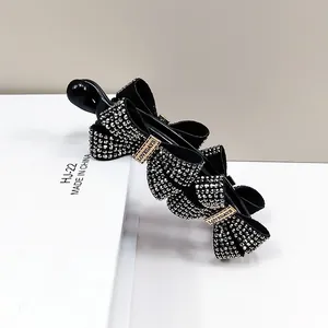 Elegant black banana hair clip with three sparkling rhinestone bows and a gold buckle accent