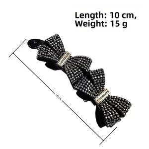 Macro detail of a 10cm black banana hair clip with crystal bows and metal engraving