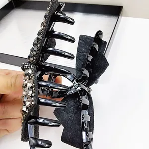 Detail of a large black claw clip with sparkling rhinestones and a delicate fabric bow