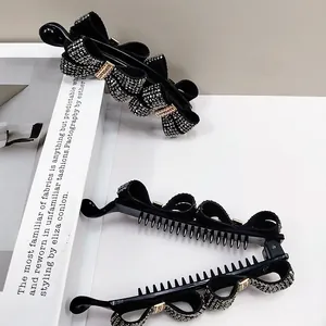 Detail of black bow banana clip with sparkling crystals and gold LOVEDAYS metal buckle