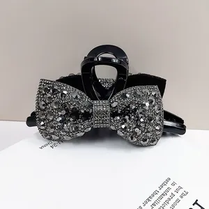 Elegant large black hair claw clip featuring a rhinestone bow design for long hair styling
