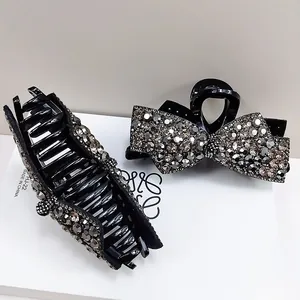 Detail showing high-gloss black bow hair claw clips with shimmering rhinestones and metal spring