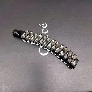 Détail macro d'une pince à cheveux banane brillante avec des cristaux gris facettés
