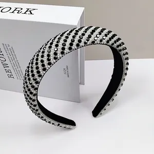 Detailed close-up of a wide headband featuring woven pearls and sparkling black rhinestones