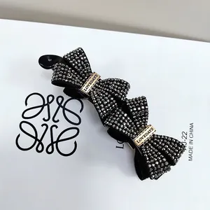 Detail of elegant black banana clip featuring crystal bow design and LOVEDAYS engraving